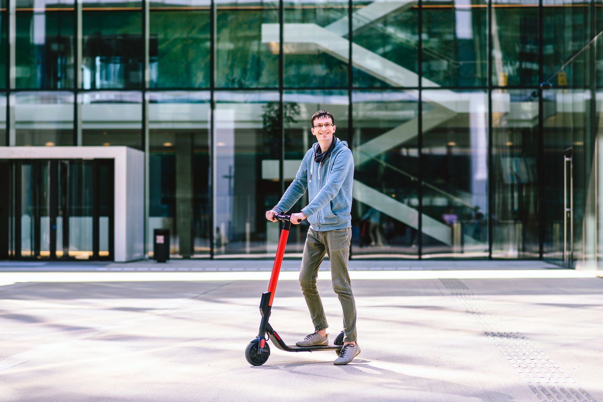Happy young man riding an electric scooter at cityscape background. Ecology transport concept.